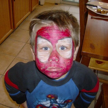 A picture of a small boy looking at the camera with Spider-Man face paint
